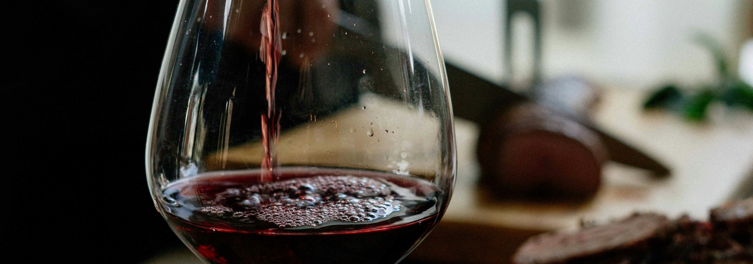 Rotwein wird am gedeckten Tisch ins Glas geschenkt